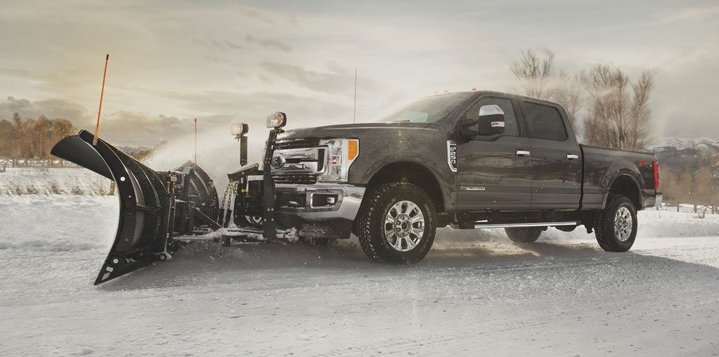 Ford Super Duty pickup with plow clearing snow.